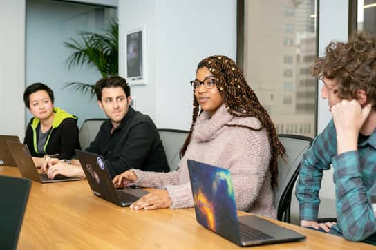 Team members reviewing work together around a laptop.